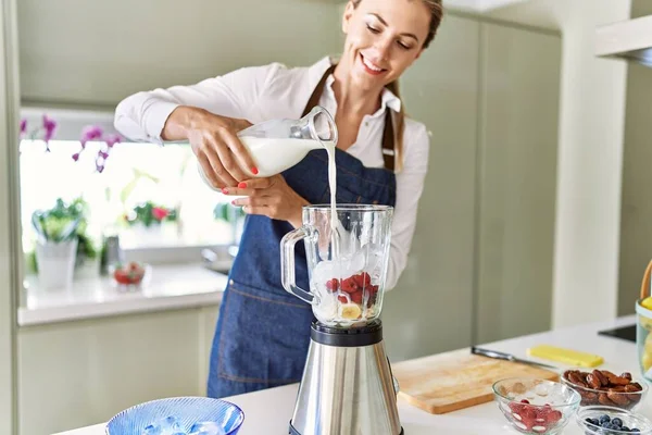 Genç Sarışın Kadın Mutfaktaki Miksere Süt Dökerek Gülümsüyor — Stok fotoğraf