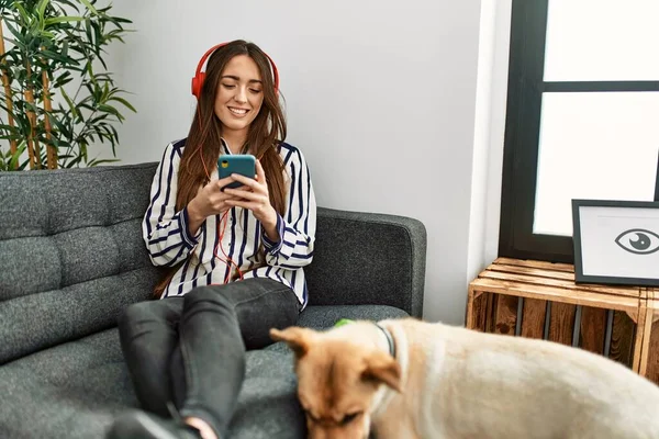 Jonge Spaanse Vrouw Met Smartphone Zittend Bank Met Hond Thuis — Stockfoto