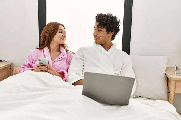 Casal Jovem Sorrindo Feliz Usando Laptop Smartphone Quarto — Fotografia de Stock