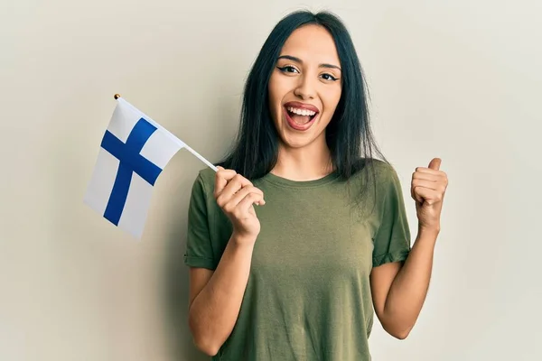 Jovem Hispânica Segurando Bandeira Finlândia Apontando Polegar Para Lado Sorrindo — Fotografia de Stock