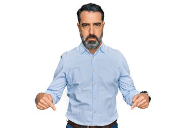 Orta yaşlı, sakallı, iş gömleği giyen üzgün ve üzgün görünen, parmaklarıyla yön gösteren mutsuz ve depresif bir adam.. 