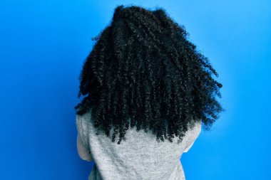 Afro saçlı, kışlık süveter giyen, kollarını kavuşturup arkasını dönen Afro-Amerikan bir kadın. 