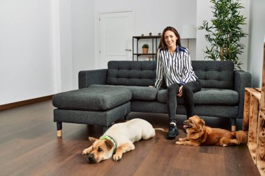 Kanepede oturmuş köpeklerle gülümseyen İspanyol bir kadın.