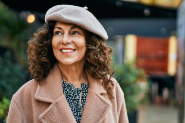 Orta yaşlı İspanyol kadın gülümseyerek şehirde mutlu mesut dikiliyor..