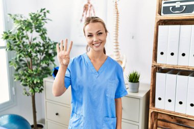 Ağrı kesici kliniğinde çalışan beyaz bir kadın dört numarayı gösterip işaret ederken kendinden emin ve mutlu bir şekilde gülümsüyor.. 