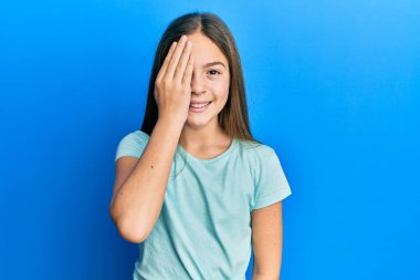 Güzel, esmer, beyaz tişörtlü bir kız bir gözünü eliyle kapatıyor, yüzünde kendine güvenen bir gülümseme ve sürpriz bir duygu var.. 