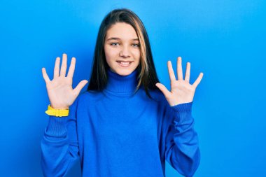 Balıkçı yaka kazak giyen genç esmer kız parmaklarını gösterip on numarayı gösterirken kendinden emin ve mutlu bir şekilde gülümsüyor.. 