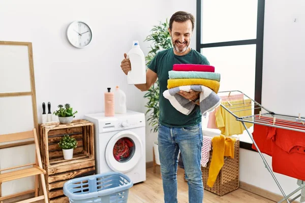 Homem Hispânico Meia Idade Fazendo Lavanderia Segurando Garrafa Detergente Roupas — Fotografia de Stock