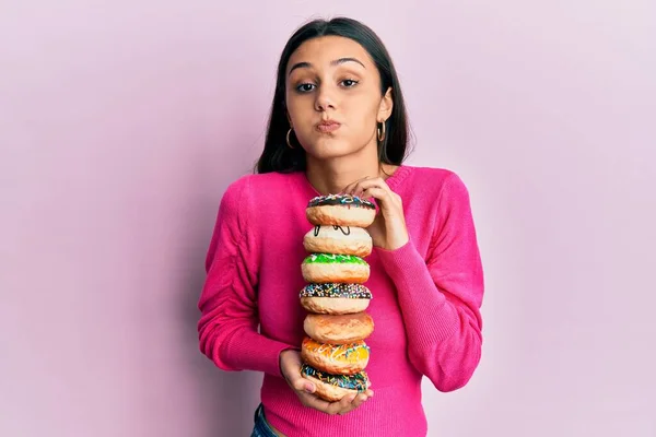 Mulher Hispânica Jovem Segurando Pilha Saborosos Donuts Coloridos Soprando Bochechas — Fotografia de Stock