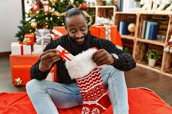 Young African American Man Holding Gift Christmas Sock Home — Stock Photo, Image