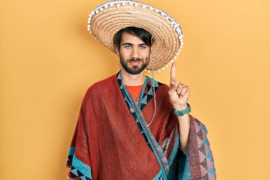 Meksikalı şapkalı genç İspanyol bir numarayı gösterip işaret ederken kendinden emin ve mutlu gülümsüyor.. 