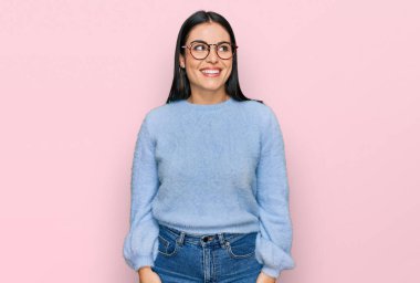 Gündelik giysiler ve gözlük takan genç İspanyol kadın yüzünde gülümsemeyle yan yana bakıyor, doğal bir ifade. Kendinden emin gülen. 