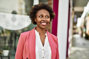 Güzel bir iş adamı Afro saçlı Amerikalı kadın şehirde mutlu ve kendinden emin bir şekilde gülümsüyor.
