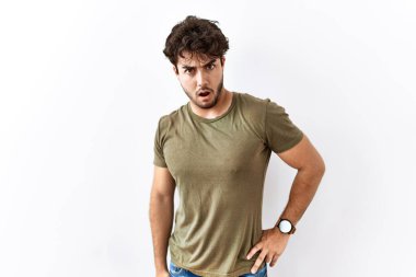 Hispanik adam şok olmuş beyaz arka planda duruyor, şüpheci ve alaycı görünüyor, ağzı açık kalınca şaşırıyor. 