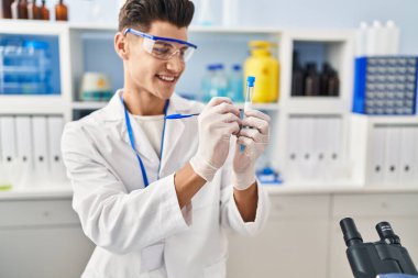 Laboratuvarda test tüpünde yazan bilim adamı üniforması giyen İspanyol genç adam.