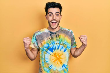 Gündelik giysiler giyen genç İspanyol adam şaşkınlık ve şaşkınlık içinde kollarını kaldırarak ve gözlerini açarak başarıyı kutluyor. Kazanan konsept. 