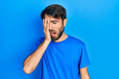 Latin asıllı genç bir adam günlük kıyafetler giyiyor. Yarı yüzünü, göz ve ağzını eliyle kapatmaktan yoruluyor. Yüzüm acıyor.. 