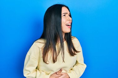 Genç esmer kadın, mide bulantısı, acı verici bir hastalık yüzünden eli karnında sıradan bir kazak giyiyor. Ağrı kavramı. 