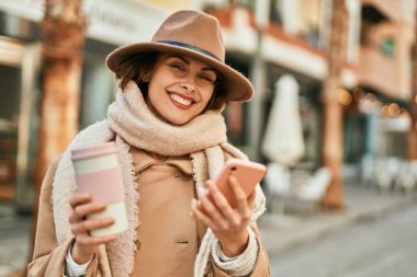 Genç İspanyol kadın akıllı telefon kullanıyor ve şehirde kahve içiyor..