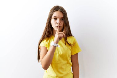 Genç esmer kız izole edilmiş arka planda yan yana duruyor ve parmakları dudaklarında sessiz olmak istiyor. sessizlik ve gizli konsept. 