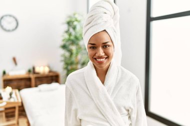 Güzellik merkezinde bornoz giyen genç Latin kadın.