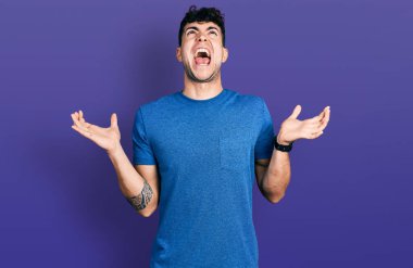 Günlük tişört giyen genç İspanyol adam deli gibi bağırıyor, agresif bir ifadeyle bağırıyor ve kollarını kaldırıyor. hüsran kavramı. 