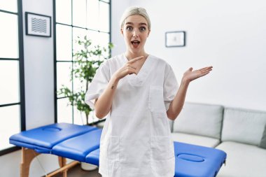 Kafkasyalı genç fizyoterapist kadın evde çalışırken kameraya hayret ediyor ve gülümsüyor.. 