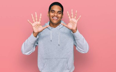 Genç, yakışıklı, sıradan bir kazak giyen, on numarayı gösteren ve gülümseyen, kendinden emin ve mutlu bir İspanyol.. 