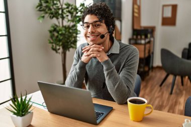 Ofiste çalışırken gülümseyen İspanyol bir çağrı merkezi ajanı..