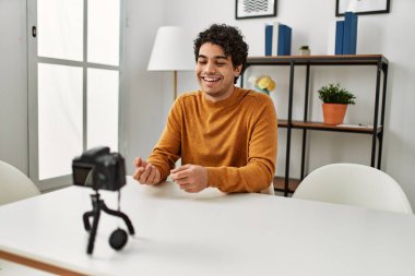 Evdeki kanepede oturan Latin asıllı genç bir adam kamerayla görüntülü görüşme yapıyor..