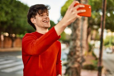Genç İspanyol gülümseyen adam şehrin akıllı telefonunda selfie çekerken mutlu oluyor..
