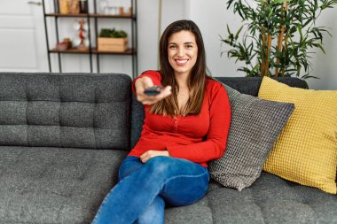 Evdeki kanepede oturan genç bir kadın.