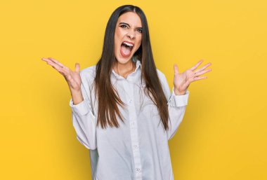 Gündelik beyaz gömlek giyen genç ve güzel bir kadın başarı için deli ve çılgınlığı kutluyor kollarını kaldırmış ve gözlerini kapatmış heyecanla bağırıyor. Kazanan konsept 