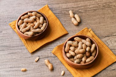 Tahta bir masada kasedeki fıstık demeti.