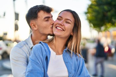 Genç adam ve kadın çift birbirlerine sarılıyor ve öpüşüyorlar.