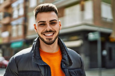 Yakışıklı, sakallı, neşeli ve kendine güvenen, kışlık palto giyen bir İspanyol.