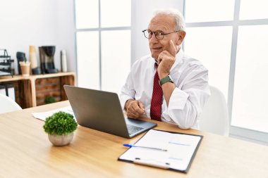 Ofiste çalışan kıdemli bir adam bilgisayar kullanıyor. Bir soru hakkında endişeli ve gergin düşünüyor. 