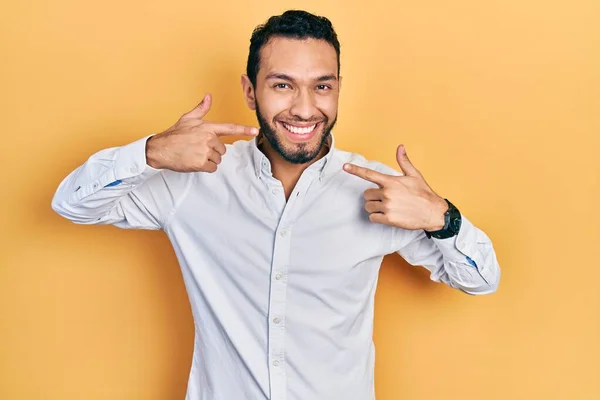 ビジネスシャツを着て髭を生やしたヒスパニック系の男は 陽気な笑みを浮かべて指の歯と口を指しています 歯の健康の概念 — ストック写真