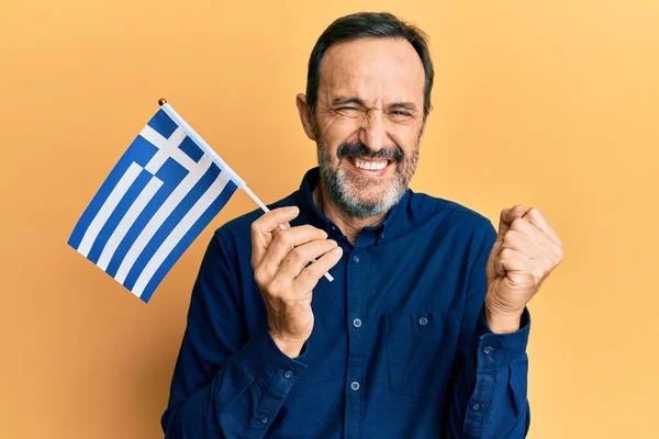 Homem Hispânico Meia Idade Segurando Bandeira Grega Gritando Orgulhoso Celebrando — Fotografia de Stock
