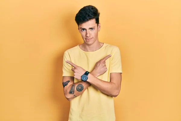 Joven Hombre Hispano Con Camiseta Amarilla Casual Apuntando Ambos Lados —  Fotos de Stock