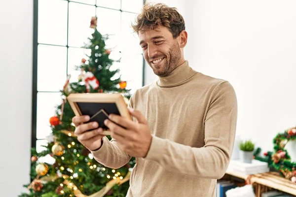 Joven Hispano Sosteniendo Foto Pie Junto Árbol Navidad Casa — Foto de Stock