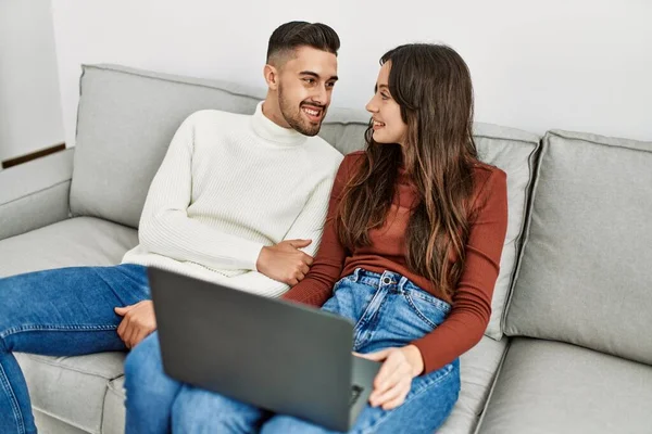他的年轻夫妇坐在家里沙发上 用笔记本电脑 — 图库照片