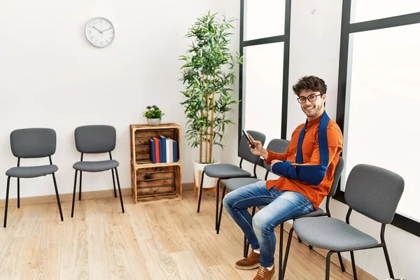 Genç İspanyol adam, klinikteki bekleme odasında sandalyeye otururken akıllı telefon kullanarak yaralandı.