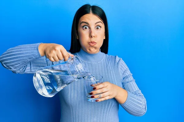 Mooie Brunette Vrouw Gieten Water Glas Puffen Wangen Met Grappig — Stockfoto