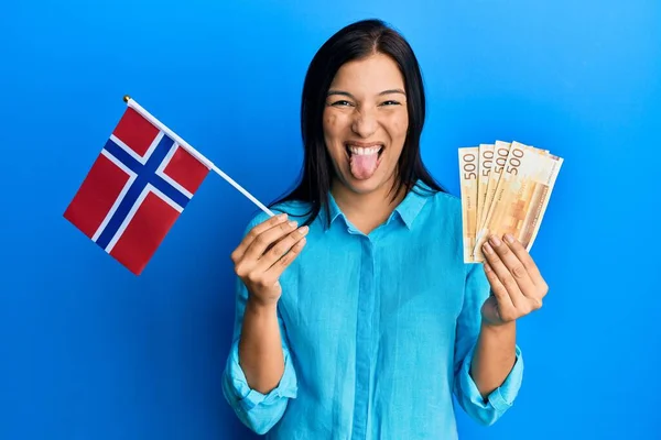Молодая Латиноамериканка Норвейским Флагом Банкнотами Крон Торчащими Языком Довольна Смешным — стоковое фото