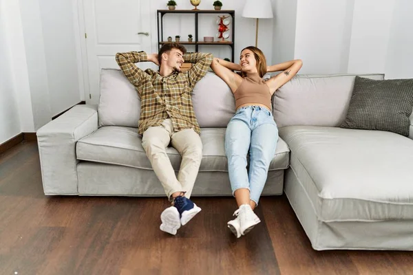 Young Hispanic Couple Relaxed Hands Head Sitting Sofa Home — Stockfoto