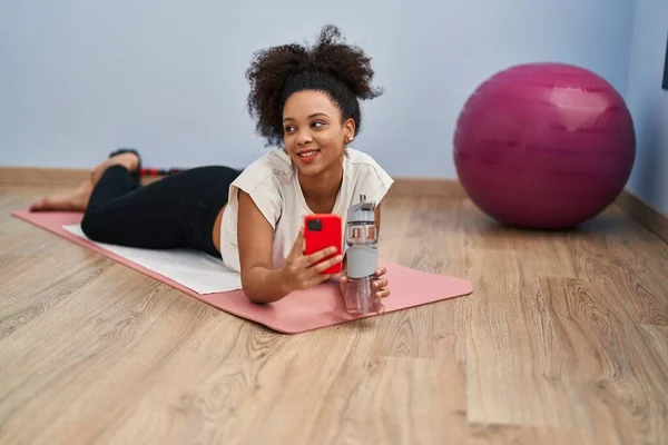 Mujer Afroamericana Joven Sonriendo Confiada Usando Teléfono Inteligente Centro Deportivo —  Fotos de Stock