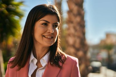 Zarif bir ceket giyen güzel İspanyol iş kadını şehirde mutlu bir şekilde gülümsüyor.