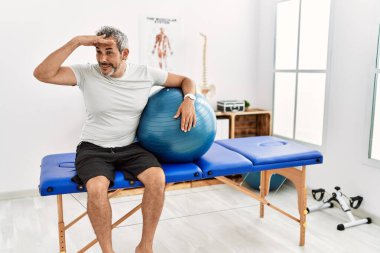 Orta yaşlı İspanyol bir adam ağrı kesici kliniğinde pilates topunu tutarken çok mutlu ve tebessüm ediyor. arama kavramı. 