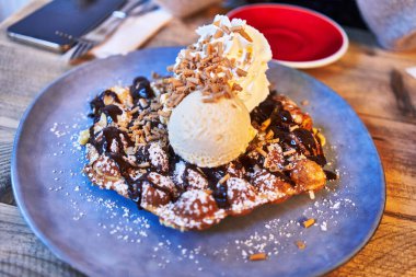  Çikolata soslu waffle tabağı ve ahşap yüzeyde dondurma.